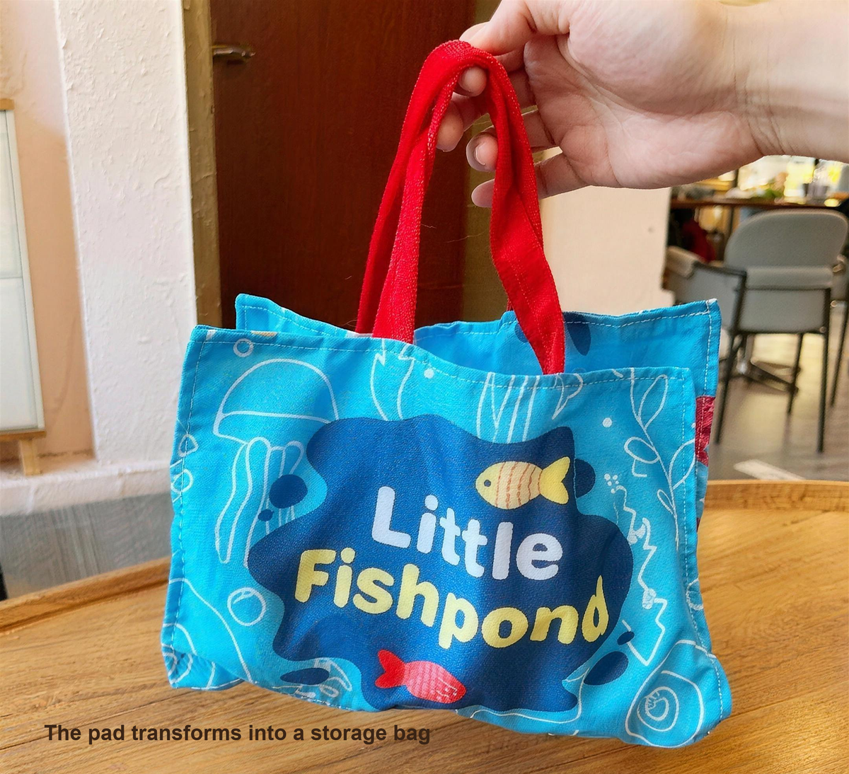 The play mat transforms into a storage bag with red carry handles